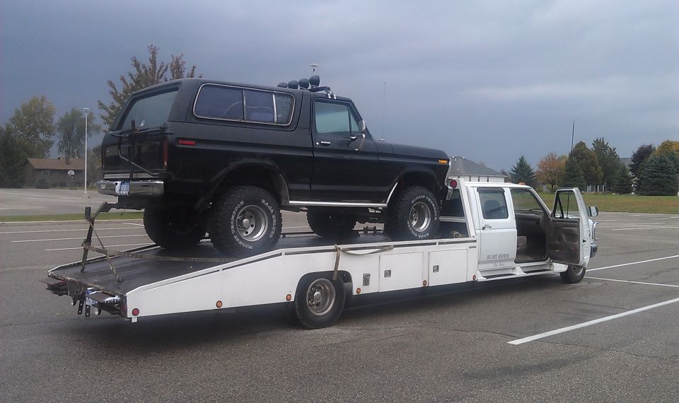 Black 1978 Ford Bronco loaded onto a white car carrier truck