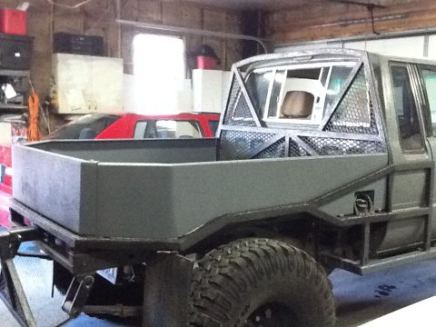 1988 Suzuki Samurai - A custom flatbed truck is parked in a garage, with a red car visible in the background.