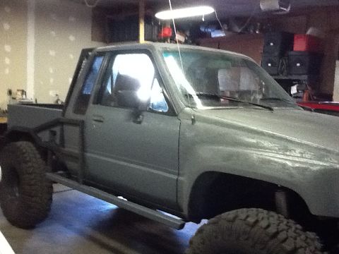 1988 Suzuki Samurai - This gray pickup truck features a custom roll cage and oversized tires, suggesting off-road modifications.