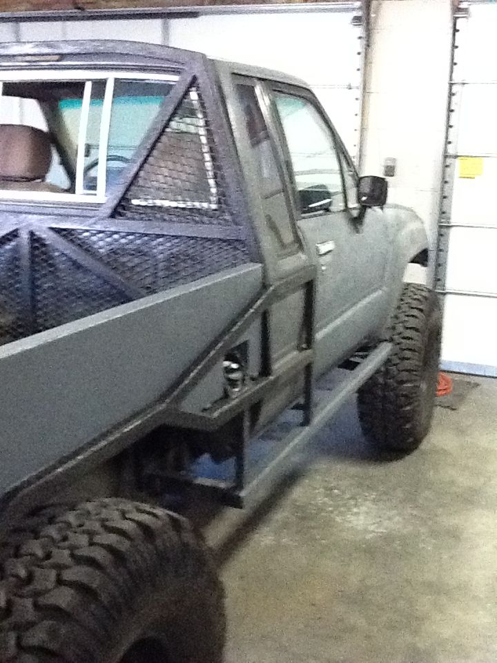 Modified pickup truck with custom bed and roll cage, side view. Appears to be a Toyota Hilux