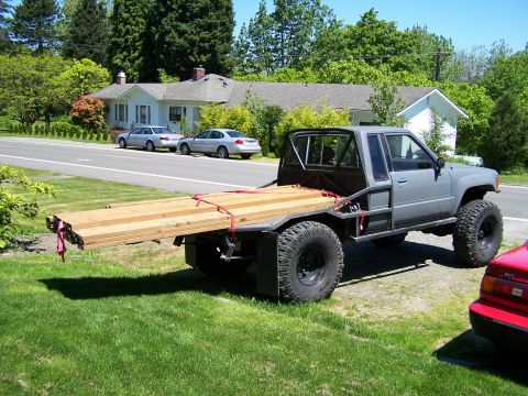 1988 Suzuki Samurai - A modified flatbed truck is parked on a lawn next to a street with two sedans.