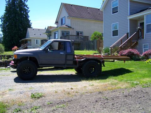 1988 Suzuki Samurai - This modified pickup truck features a flatbed and oversized tires, suggesting off-road capabilities.