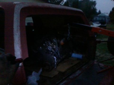 1981 Ford Bronco - Engine being lowered into a red truck, possibly for an engine swap.
