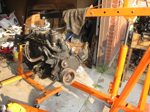 1981 Ford Bronco - An engine is suspended on an orange engine stand, likely for removal or installation.