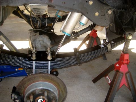 1996 Ford Bronco - The rear suspension components of a vehicle are supported by jack stands and a blue jack.