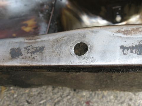 1981 Ford Bronco - A close-up view of a metal frame section, showing a drilled hole and the 'SUPERMOTORS' website logo.