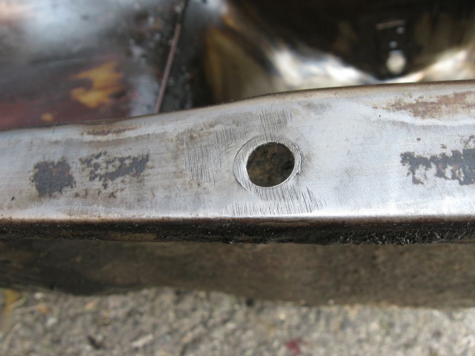 Close-up of a metal frame with a drilled hole and visible text 'SUPERMOTORS'