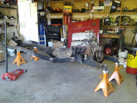1968 Ford Bronco - Vehicle frame and powertrain components are disassembled and supported by jack stands in a garage.