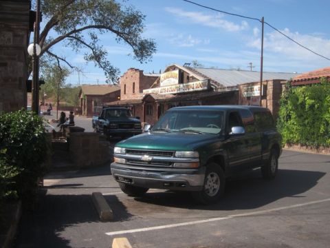 1991 Ford LTD Crown Victoria - A green SUV is parked in a lot with a dark pickup truck in the background, in front of a building with signage.
