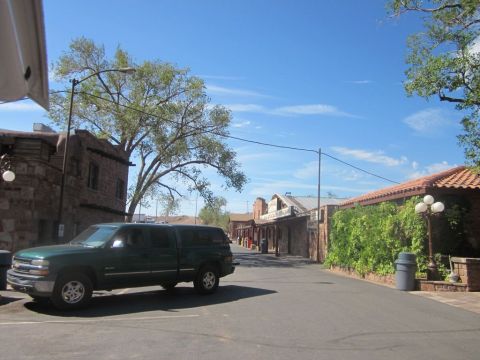 1991 Ford LTD Crown Victoria - A green pickup truck with a camper shell is parked on a street lined with buildings that appear to be from an older era.