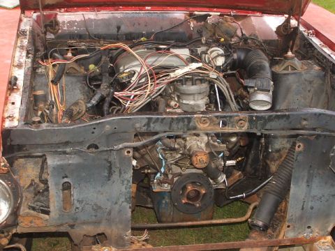 1966 Ford Ranchero - The engine bay of a vehicle is shown with many wires and engine parts exposed.