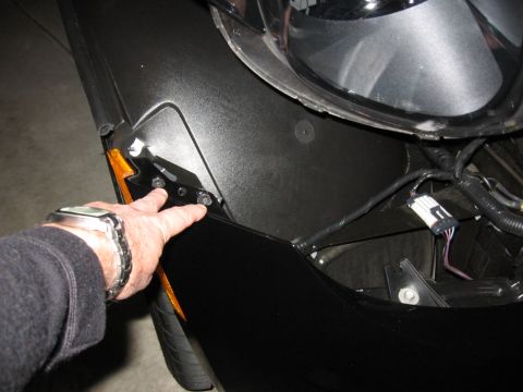1995 Ford Bronco - Close-up of a hand indicating mounting bolts on a vehicle's fender assembly.
