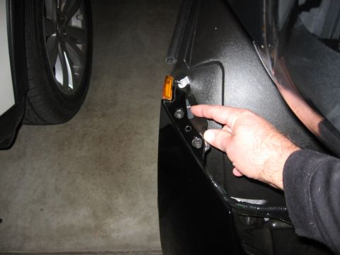 1995 Ford Bronco - A person's hand is shown pointing to a detached orange marker light on the fender of a black vehicle.