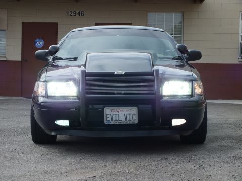 2003 Ford Crown Victoria - cowl-hood Crown Victoria faces the camera with all lights on and a CROWN VICTORIA plate frame.