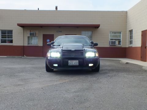 2003 Ford Crown Victoria - Headlamps glow on this dark Crown Victoria parked across an empty asphalt lot at 12946.