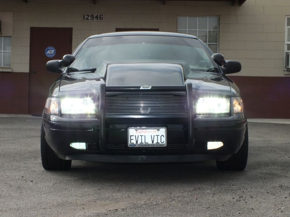 Front of black Ford Crown Victoria with grille guard, cowl hood and EVIL VIC license plate