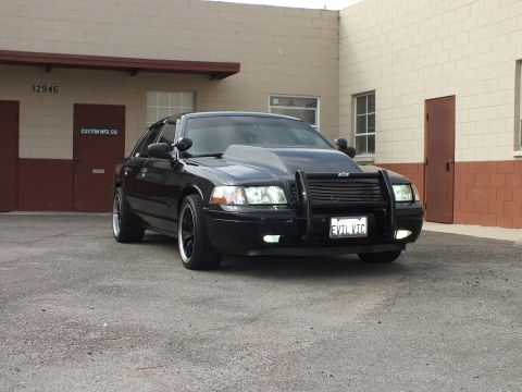 2003 Ford Crown Victoria - Angled view of the EVIL VIC Crown Victoria beside a door marked CUSTOM MFG CO.