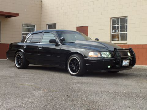 2003 Ford Crown Victoria - Polished black Crown Victoria angles toward camera showing amber markers and push bar.