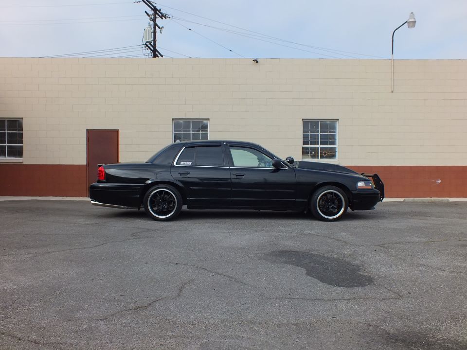 Black Ford Crown Victoria sedan, passenger side, lowered on black wheels with front bull bar