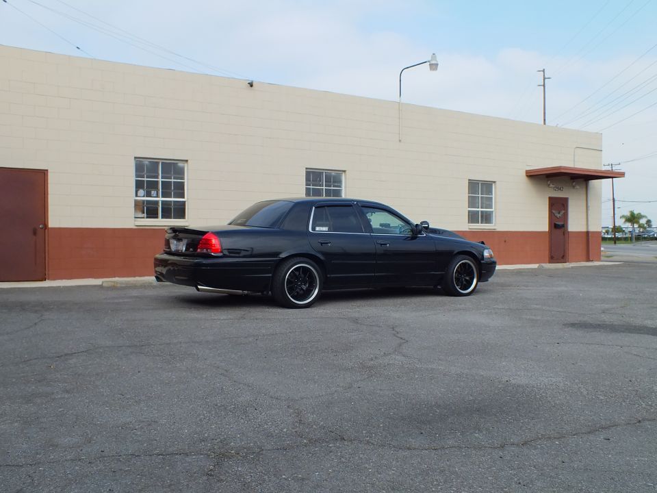 Black Ford Crown Victoria sedan, rear driver side, lowered on black wheels with trunk spoiler