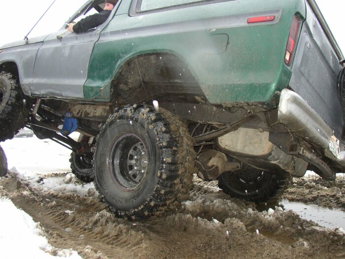 Lifted green Ford Bronco on big mud tires in deep mud and snow