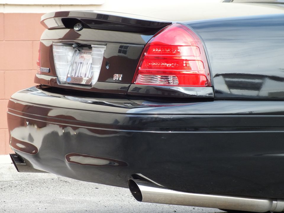 Close-up of black Crown Victoria rear showing EVIL VIC plate, SVT badge and chrome exhaust