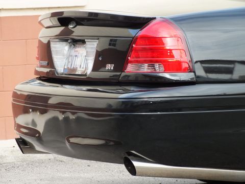 2003 Ford Crown Victoria - Detail shot of a black sedan's rear corner with SVT badge, red taillight and polished exhaust.