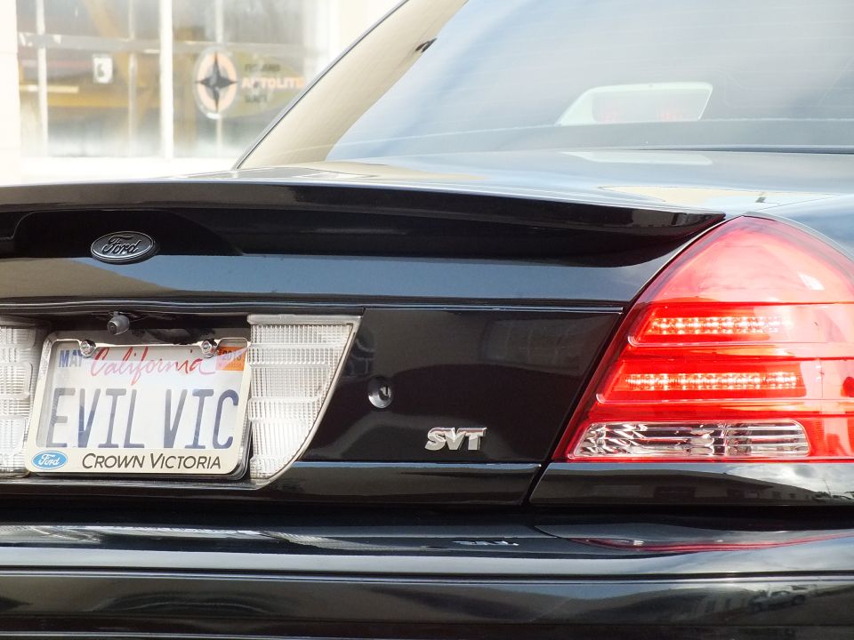 Close-up of black Crown Victoria trunk with Ford oval, EVIL VIC California plate and SVT badge