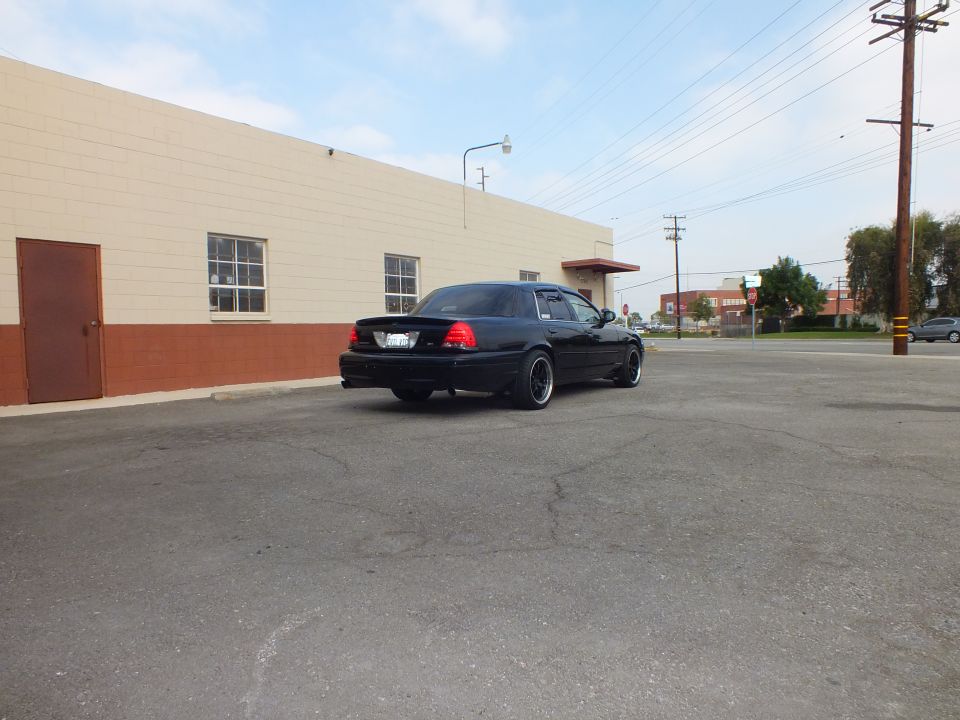 Black Ford Crown Victoria sedan, rear driver side, distant view in paved lot near street
