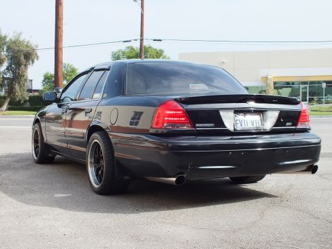 2003 Ford Crown Victoria - Rear three-quarter of black Crown Victoria with EVIL VIC plate and black aftermarket wheels