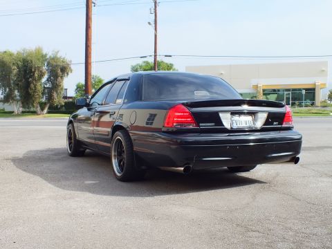 2003 Ford Crown Victoria - Left rear quarter view of lowered black Crown Victoria sedan in an open lot