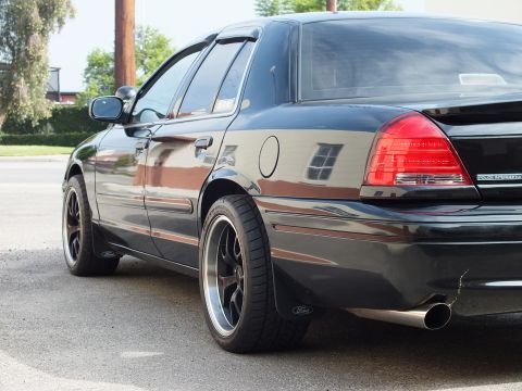 2003 Ford Crown Victoria - Close rear quarter of black Crown Victoria showing taillight, black wheel and Ford mudflap