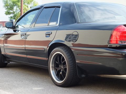 2003 Ford Crown Victoria - Side detail of black Crown Victoria showing rear door, fuel door and black aftermarket wheel