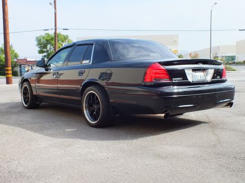 2003 Ford Crown Victoria - Left rear quarter of lowered black Crown Victoria with EVIL VIC plate on black wheels