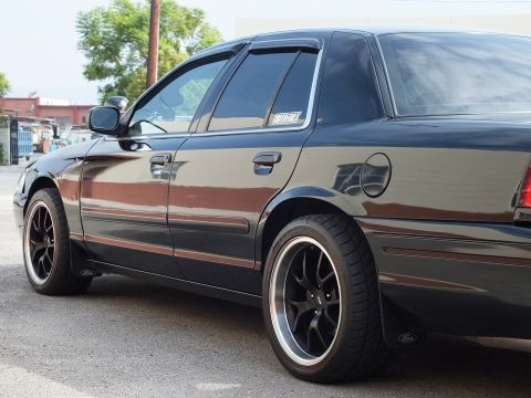 2003 Ford Crown Victoria - Side detail of black Crown Victoria showing front door, window visor and black wheel