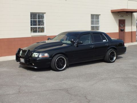 2003 Ford Crown Victoria - Front quarter of black Crown Victoria fitted with a push bar grille guard, parked by building