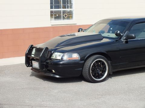 2003 Ford Crown Victoria - Close front quarter of black Crown Victoria showing grille guard, headlights and black wheel
