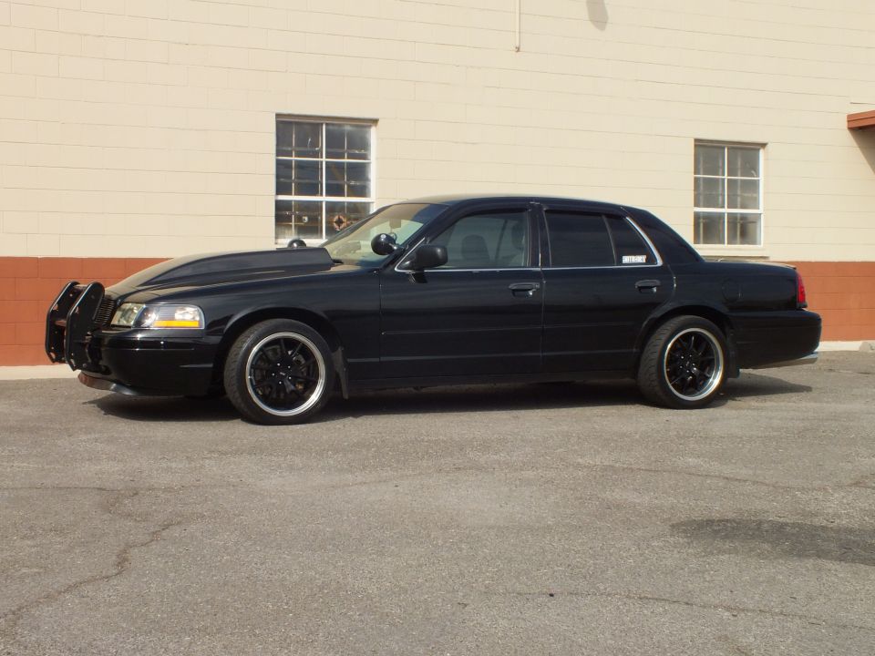 Black Ford Crown Victoria full driver-side profile, black wheels, lowered stance