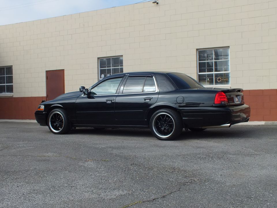 Black Ford Crown Victoria passenger-side rear three-quarter, trunk spoiler, black wheels