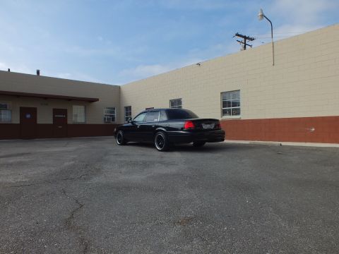 2003 Ford Crown Victoria - Wide rear view of a black Crown Victoria parked in an empty asphalt lot.