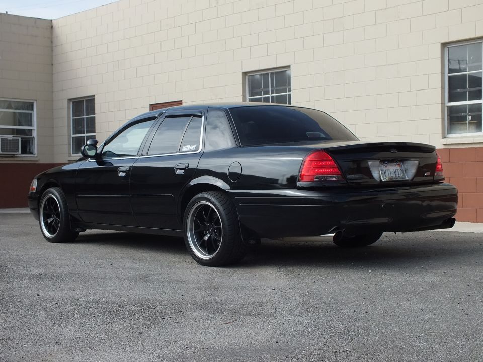 Black Ford Crown Victoria driver-side rear three-quarter, vent visors, dual exhaust