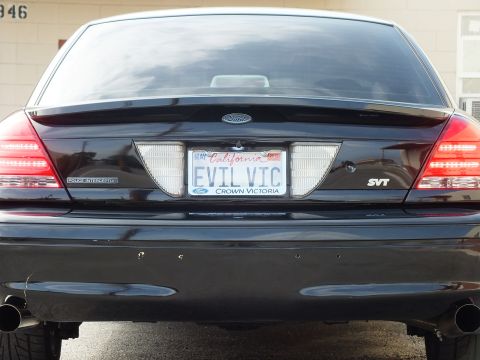 2003 Ford Crown Victoria - Trunk and tail-light view of a black Crown Victoria badged Police Interceptor and SVT, EVIL VIC plate.