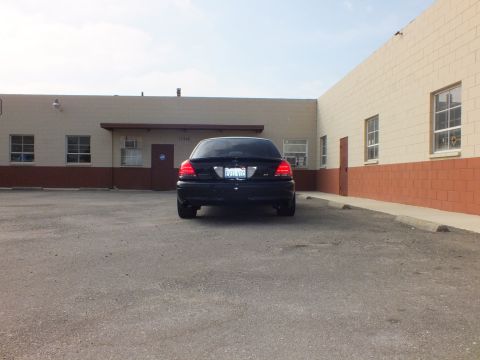 2003 Ford Crown Victoria - Distant rear view of a black Crown Victoria parked in a paved lot before a tan building.