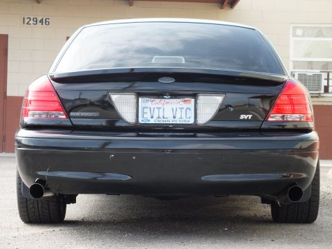 2003 Ford Crown Victoria - Black Crown Victoria SVT from behind, Ford emblem, dual exhaust tips, EVIL VIC plate.