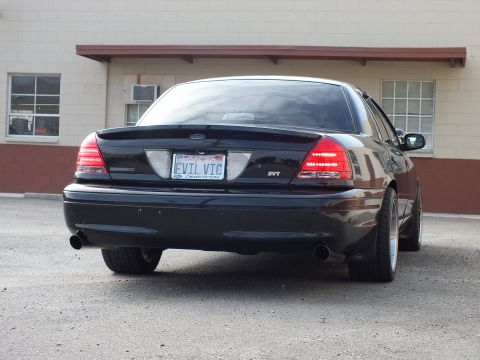 2003 Ford Crown Victoria - Black Crown Victoria SVT shown at an angle from the rear, dual exhaust and EVIL VIC plate.