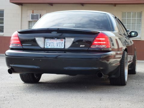 2003 Ford Crown Victoria - Low-stance black Crown Victoria SVT from a rear three-quarter angle, EVIL VIC plate, dual pipes.