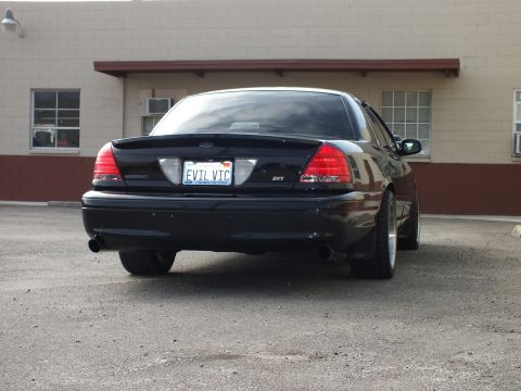 2003 Ford Crown Victoria - Black Crown Victoria SVT at a rear angle with tinted windows and EVIL VIC plate.