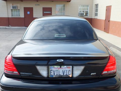 2003 Ford Crown Victoria - High rear angle of a black Crown Victoria SVT trunk lid and tinted glass, EVIL VIC plate.