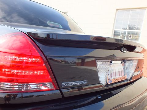 2003 Ford Crown Victoria - Tight shot of a black Crown Victoria trunk with Police Interceptor badge and lit license plate area.