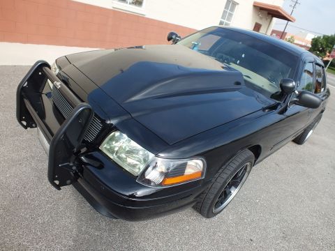 2003 Ford Crown Victoria - Front three-quarter of a black Crown Victoria fitted with a push-bar brush guard and dark wheels.